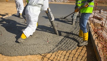 two construction workers pour concrete