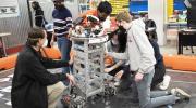 four students and professor work on a robot