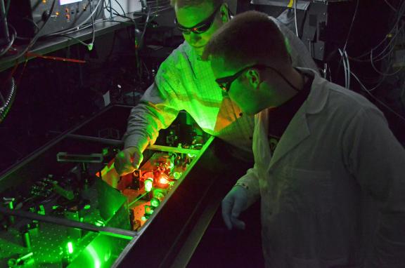 BME professor Chris Schaffer and a grad student are illuminated by green laser light in Schaffer's lab.
