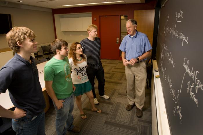 Professor talking with students at the chalk board